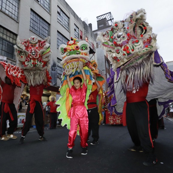 People in traditional Chinese garb dancing with giant dragon puppets in a parade