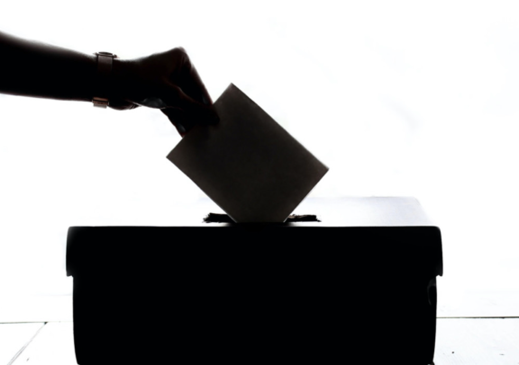 Hand placing envelope into ballot box