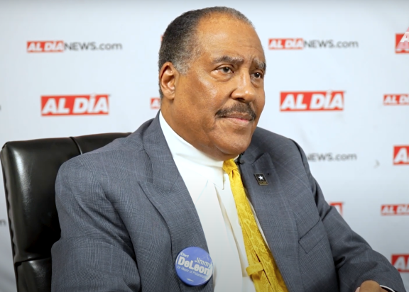 Judge James DeLeon sitting in brown chair in front of Al Día logos