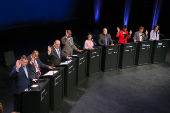 Candidates for mayor of Philadelphia raise their hands behind podiums