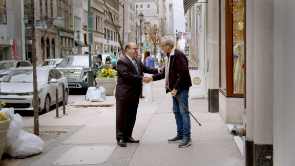 Allan Domb shaking hands with another person on the street