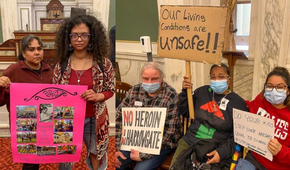 Housing activists holding up signs at city council meeting