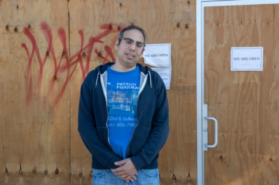 Ben Nachum, owner of Patriot Pharmacy, in front of boarded up storefront