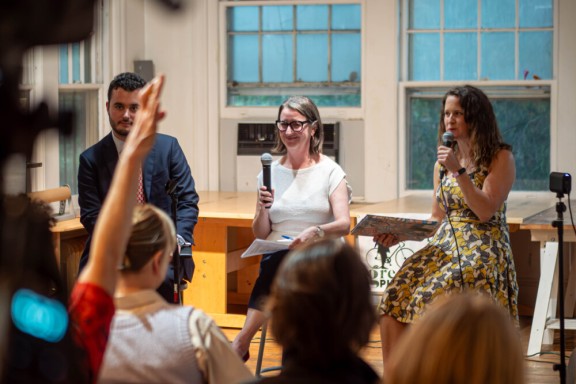 Three panelists on stage holding microphones