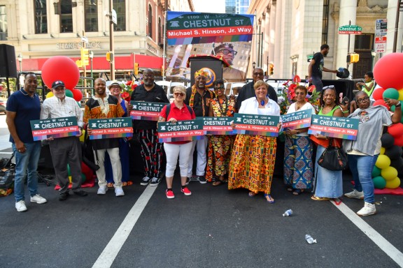 Organizers and speakers pose with signs designating the 1200 block of Chestnut Street as Michael S. Hinson Jr. Way. From left, Dr. Andre Ford, David Fair, Chris Hunter (Dashiki), Roberta Cancellier, Christopher Weaver, Tami Sortman, Lee Carson, Lanette Swopes, Kareem E. Thomas, Tara L. Webb, Rashidah Perry-Jones, Quibila Divine and Sylvia Simms. (Photo: Kelly Burkhardt)