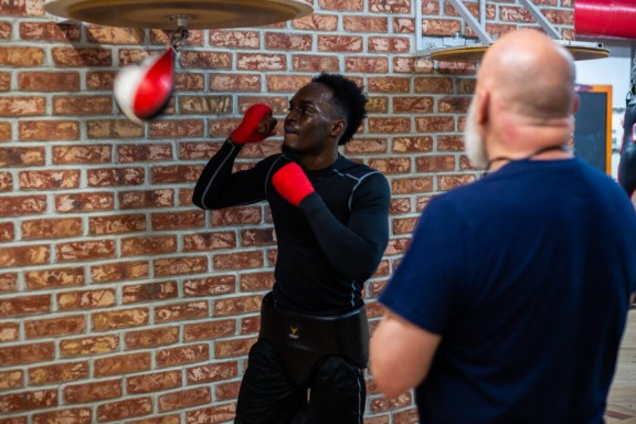 a boxing trainer and trainee using punching balloon