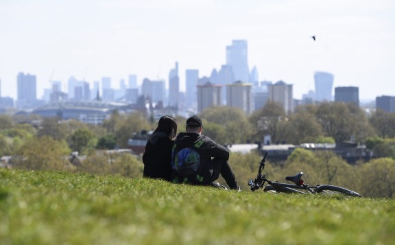 Two people and a bike on grass, Philadelphia cityscape in background (Associated Press)