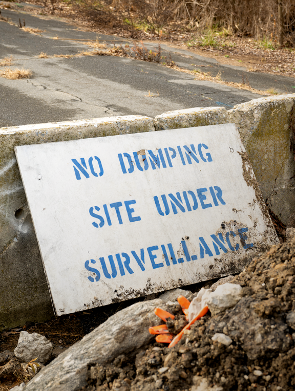 Warning signs at illegal dumping hotspots, such as at this dead end of Lyons Place in Eastwick, can only do so much to reduce the problem. Photo by Troy Bynum.