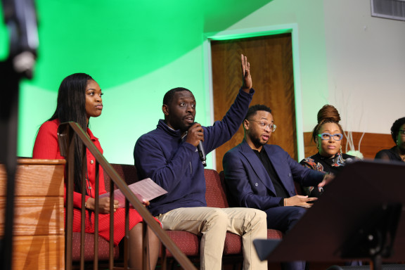 City Councilmember Isaiah Thomas raising his hand as he engages with audience at a recent panel about education funding and school closures in Philadelphia.
