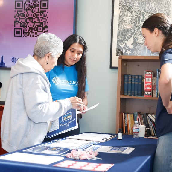 Three people standing around a table full of voter resources