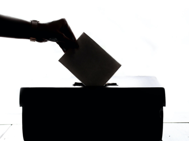 Hand placing envelope into ballot box