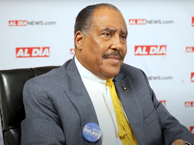 Judge James DeLeon sitting in brown chair in front of Al Día logos