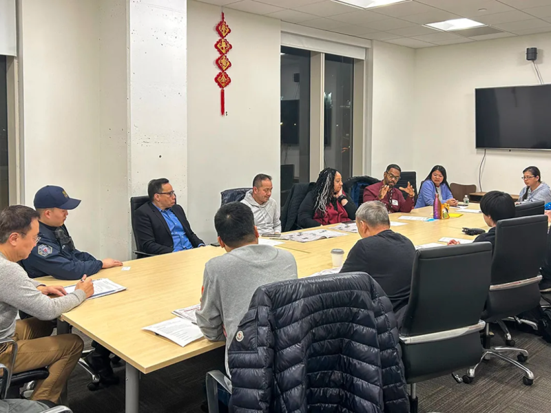 12 people sitting around a conference table 