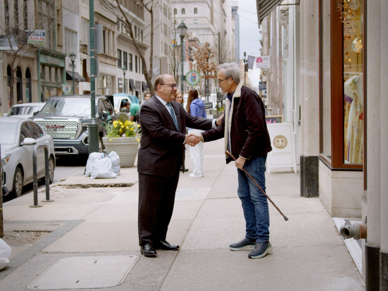 Allan Domb shaking hands with another person on the street