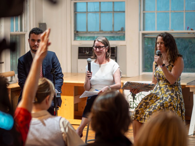 Three panelists on stage holding microphones