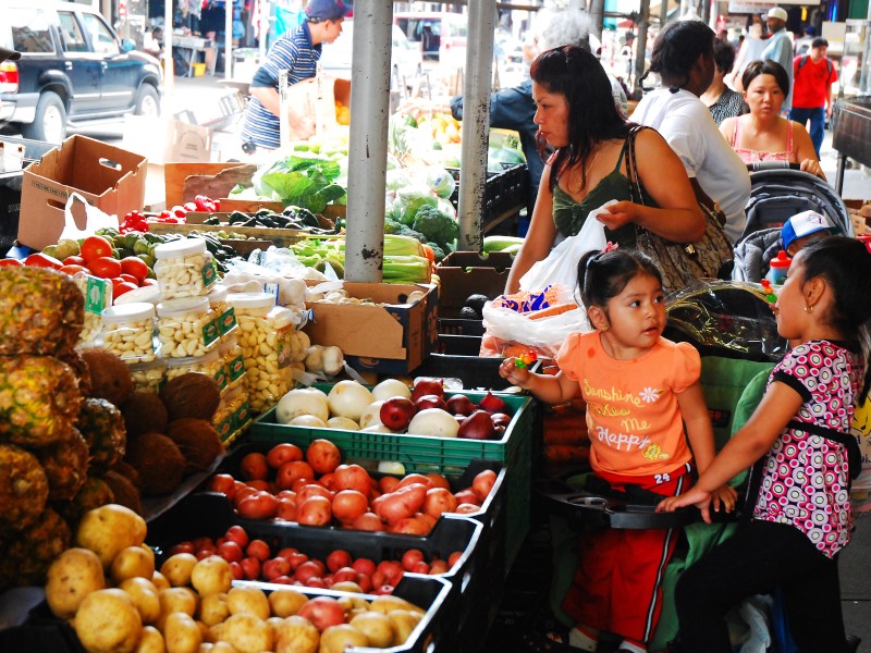 Woman and her children shopping for fruit at an outdoor market