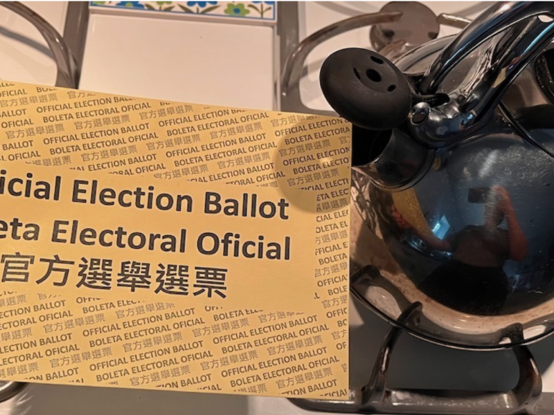 An official election ballot envelope being held near the spout of a tea kette