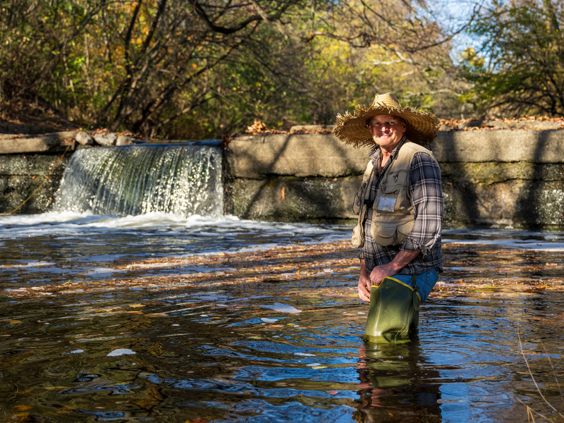 Erik Silldorff stands in Cobbs Creek in front of the Woodland Dam