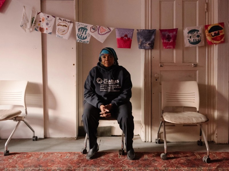 Movita Johnson-Harrell sitting in a chair in a white room with decorative flags above her