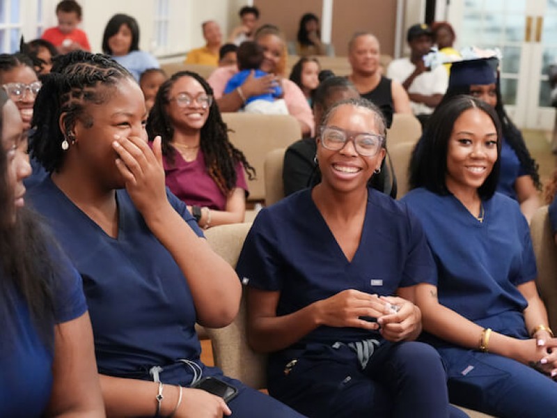 Women dressed in dark blue scrubs celebrating their graduation