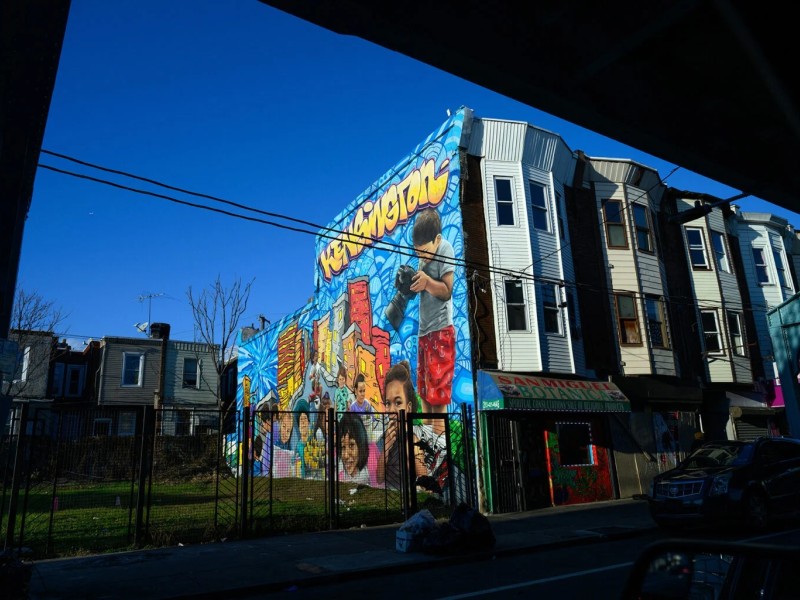 A bright colored mural of children on the side of row homes in Kensington, Philadelphia