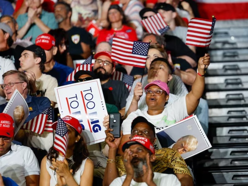 People cheering in stands at a Trump rally