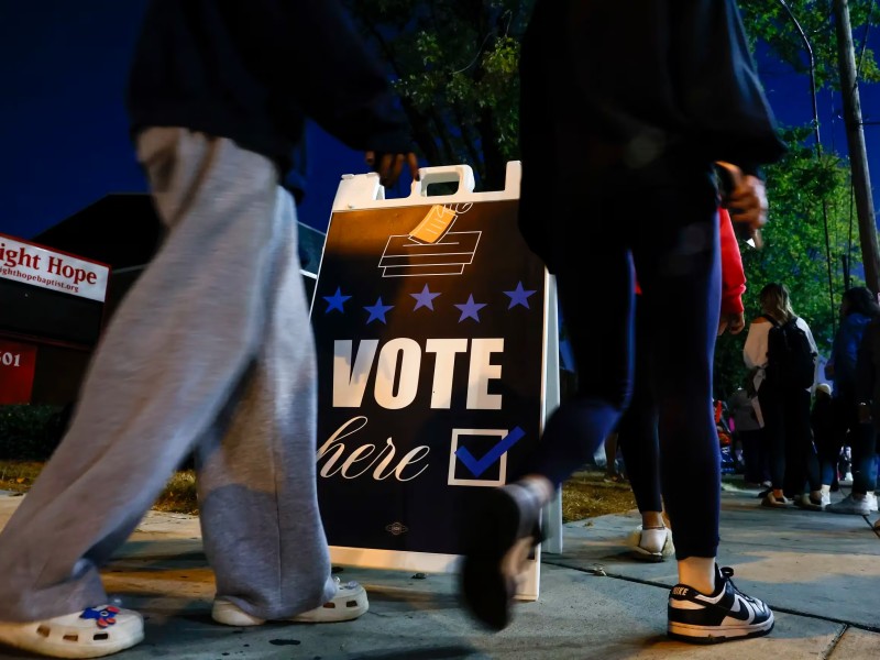 People lining up to vote near a sign saying Vote Here