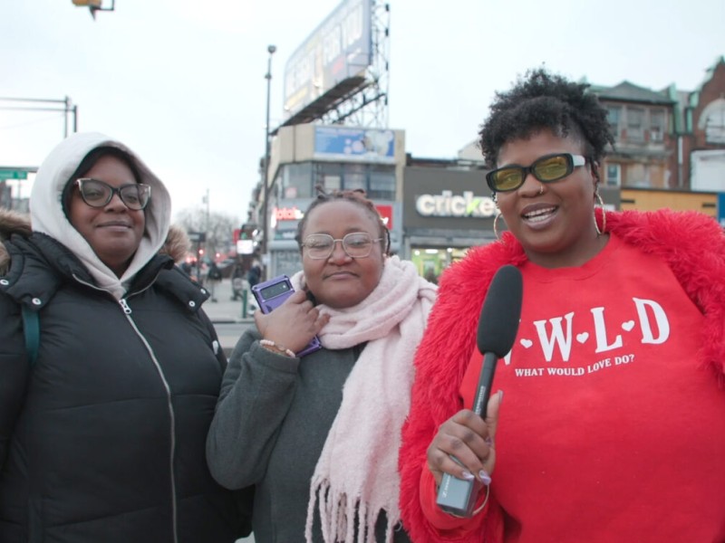 Interviewer Tata Cherise speaking into a mic next to two North Philly residents on the street 