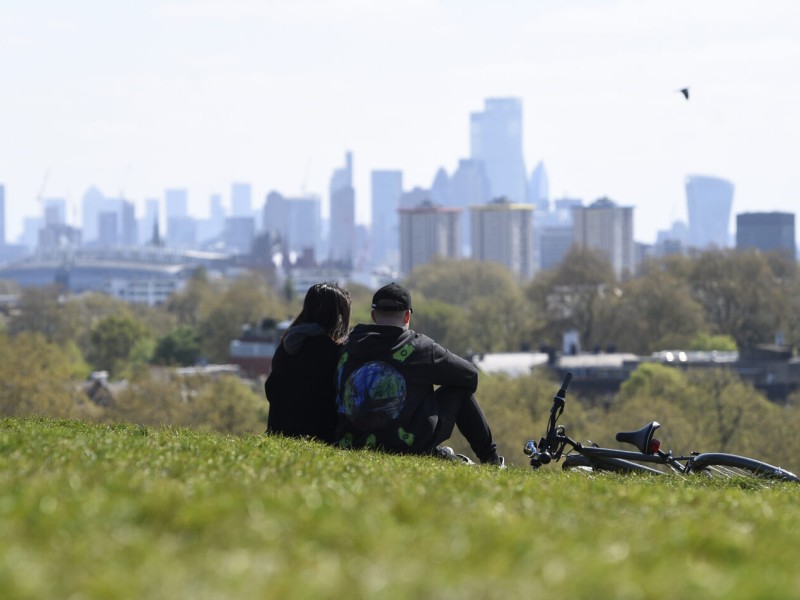 Two people and a bike on grass, Philadelphia cityscape in background (Associated Press)