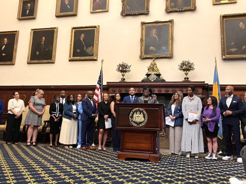 Philadelphia Mayor Cherelle Parker, flanked by Superintendent Tony Watlington and Education Chief Debora Carrera, announces that 15 new schools will participate in the “extended day, extended year” school initiative at Philadelphia City Hall on Friday, June 27, 2025. (Carly Sitrin / Chalkbeat)