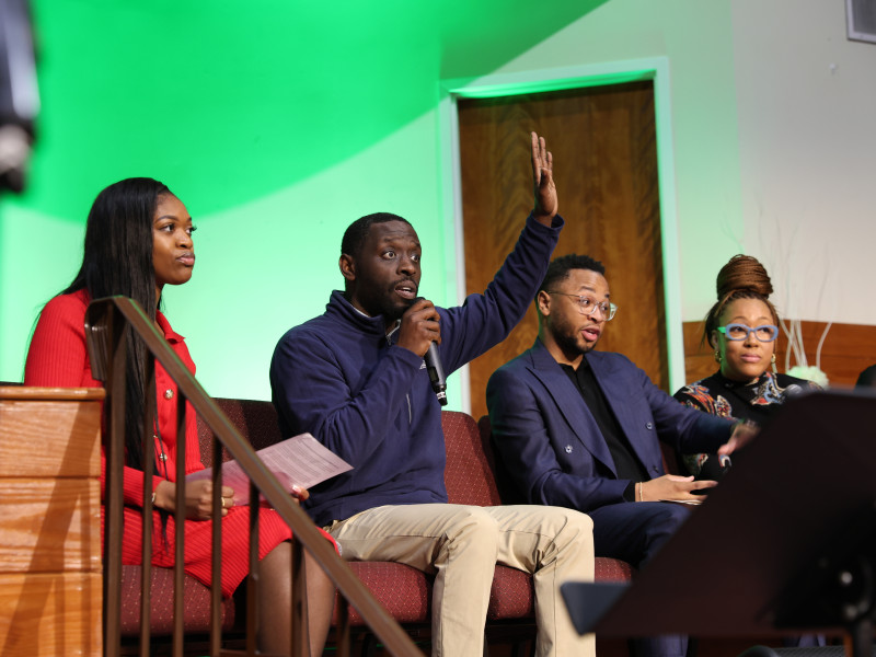 City Councilmember Isaiah Thomas raising his hand as he engages with audience at a recent panel about education funding and school closures in Philadelphia.