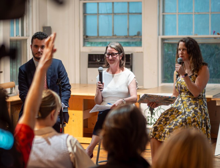 Three panelists on stage holding microphones