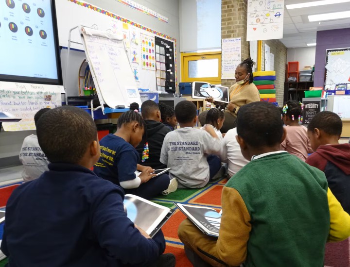 A teacher reads to a group of students at Andrew Hamilton school. A new report found that teachers in their first three years of teaching and teachers of color leave their jobs at higher rates than others. (Carly Sitrin/Chalkbeat)