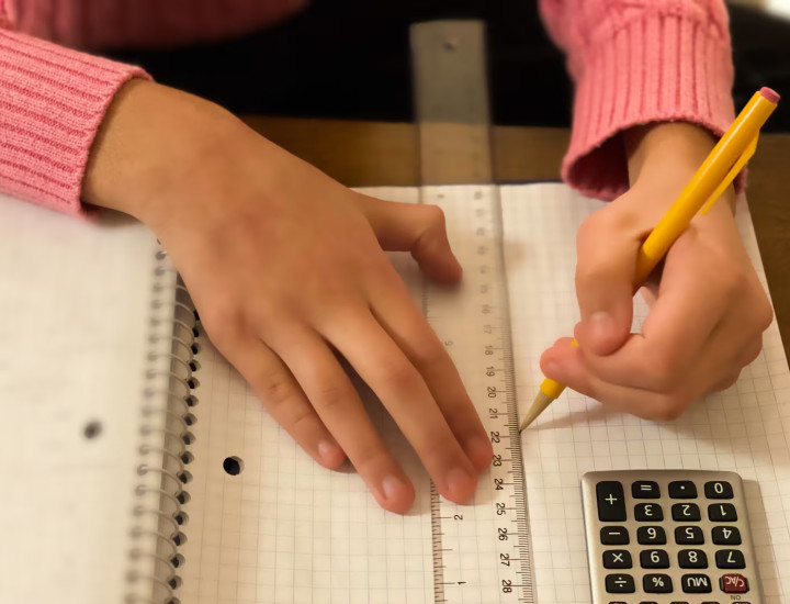 Image of a child's hand holding a pencil and a ruler